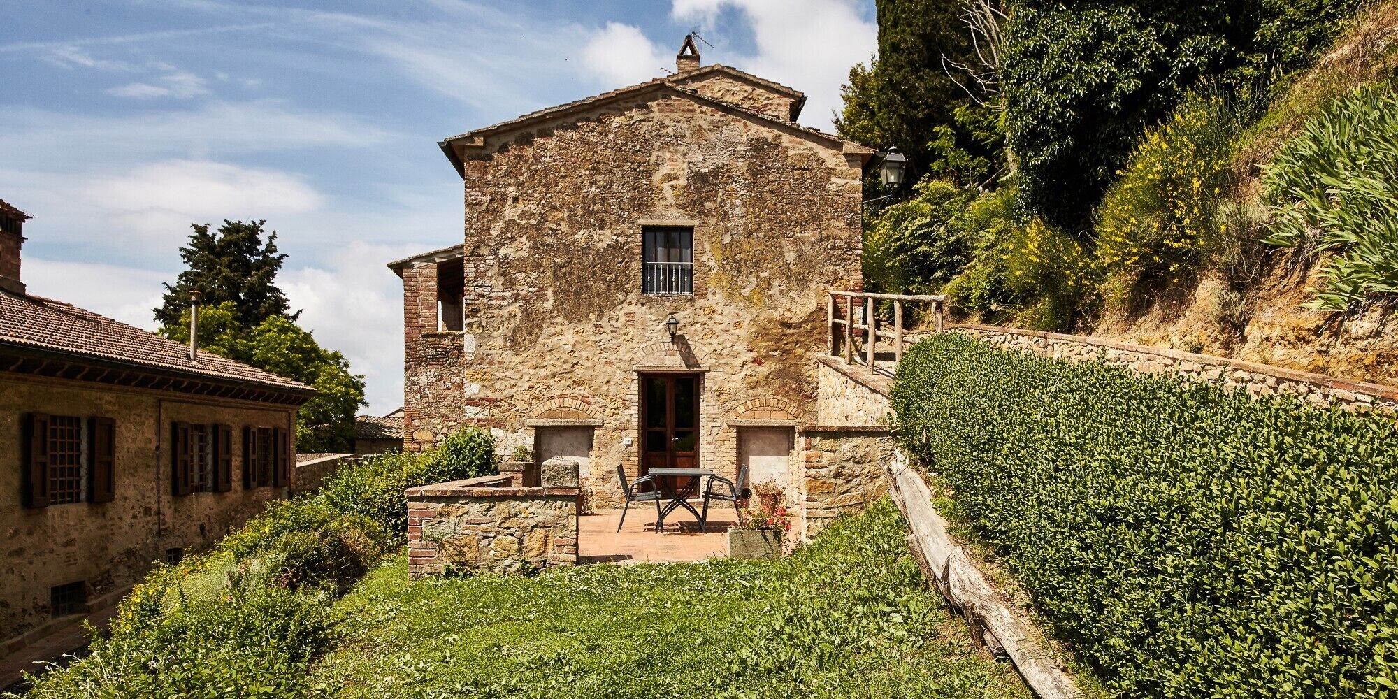 A stone building with a balcony and a table outside.