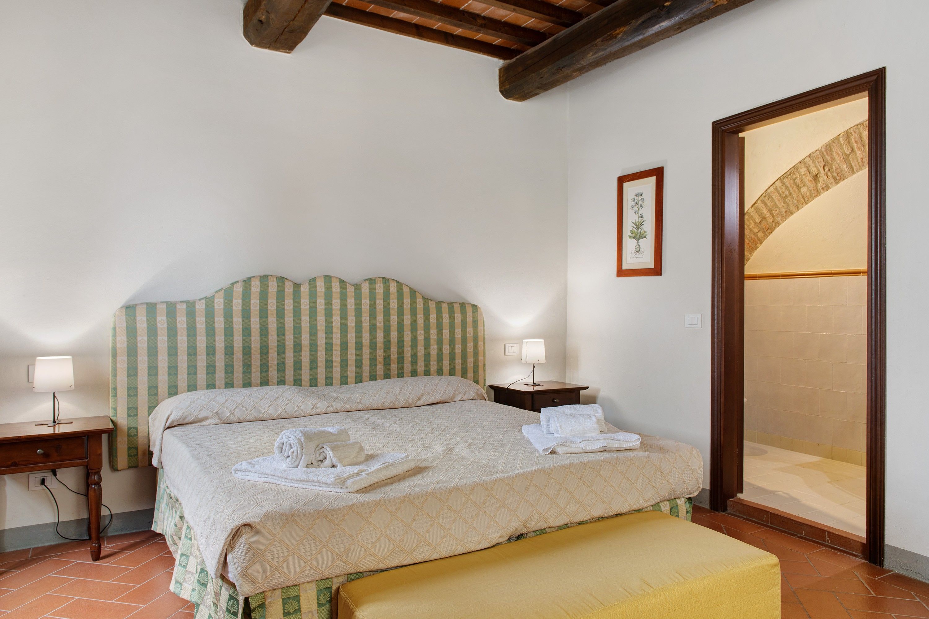 A bedroom with a bed, bedside tables, a lamp, and a large mirror.