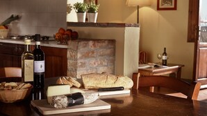 Une cuisine avec une table mise pour le repas, où l’on voit du pain, du fromage et une bouteille de vin.