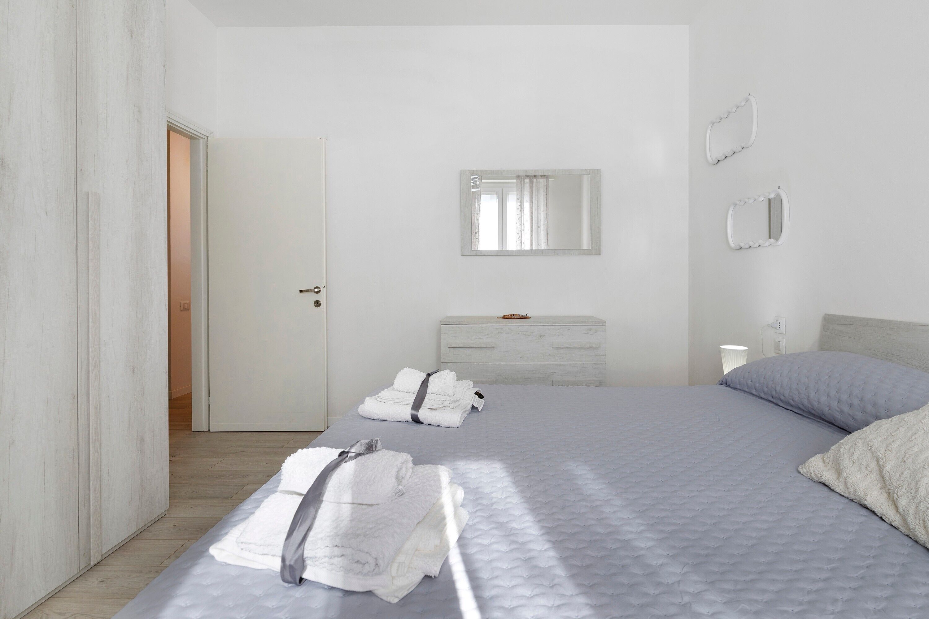 Een hotelkamer met een bed, een ladekast, een spiegel en een deur.