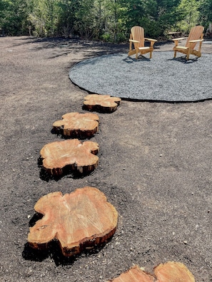 A circular seating area with Adirondack chairs and a gravel path with wooden stumps.
