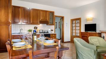 Un comedor con muebles de madera, un televisor y una cocina al fondo.