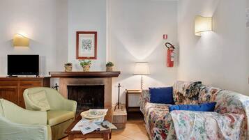 Una sala de estar con chimenea, televisor, sofá y mesa de centro.