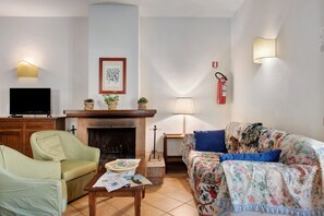 Una sala de estar con chimenea, televisor, sofá y mesa de centro.
