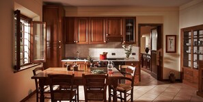 A kitchen with wooden cabinets, a dining table with chairs, and a kitchen island. - Guarda - Spacious Apartment with Fireplace and Panoramic View (Gambassi Terme)
