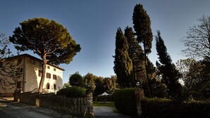 Un edificio con un muro de piedra, un árbol grande y un jardín bien cuidado.
