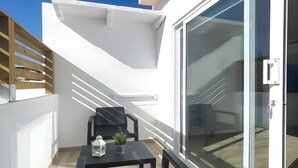 A balcony with a table, chairs, a potted plant, and a lantern. - B-Rent La Azotea Zen – Your Relaxing Oasis in Corralejo (Corralejo)