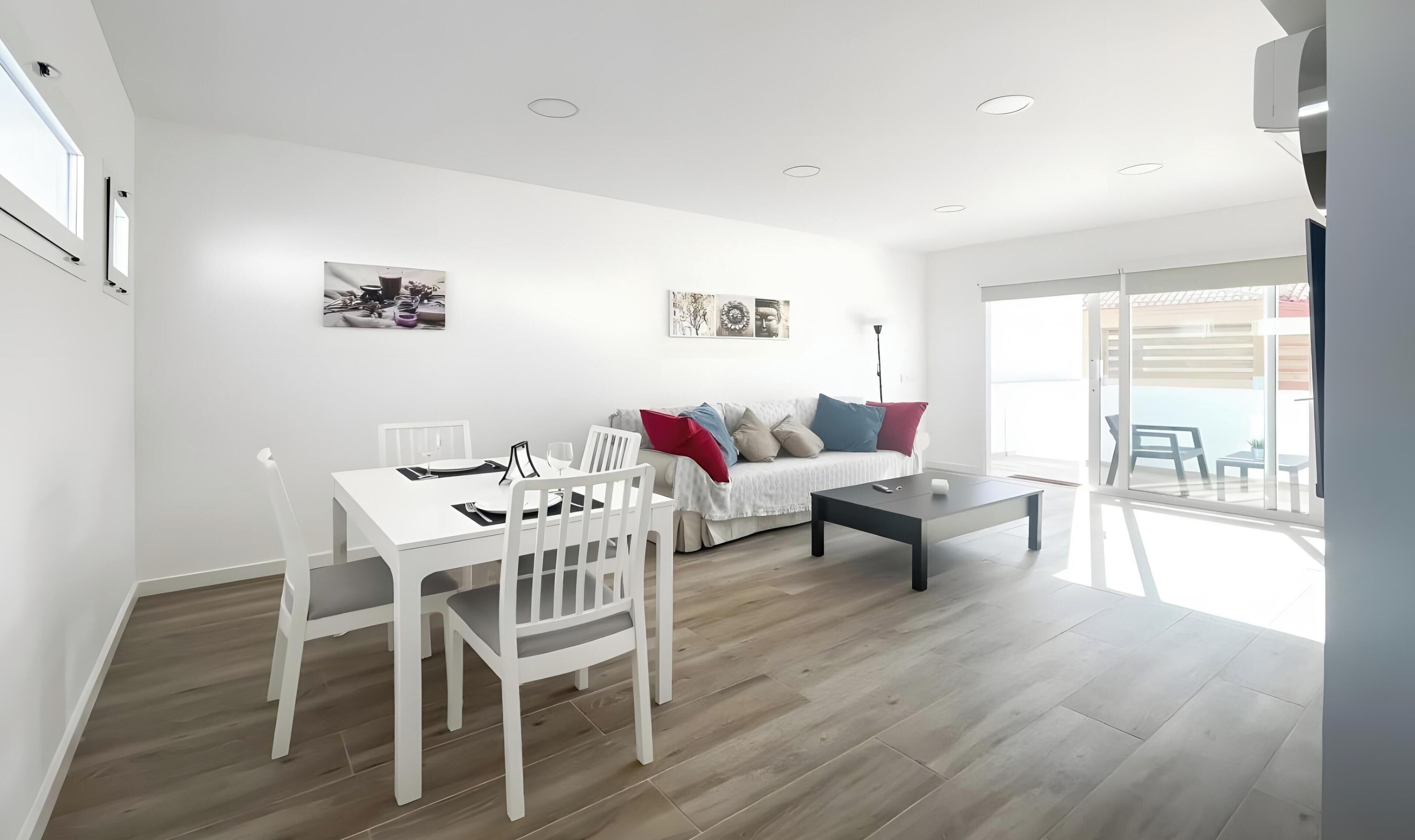 Un salon moderne comprenant un coin repas, un canapé avec des coussins et une grande fenêtre.