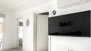 A modern kitchen with white cabinetry, a black countertop, and an air conditioning unit. - B-Rent La Azotea Zen – Your Relaxing Oasis in Corralejo (Corralejo)