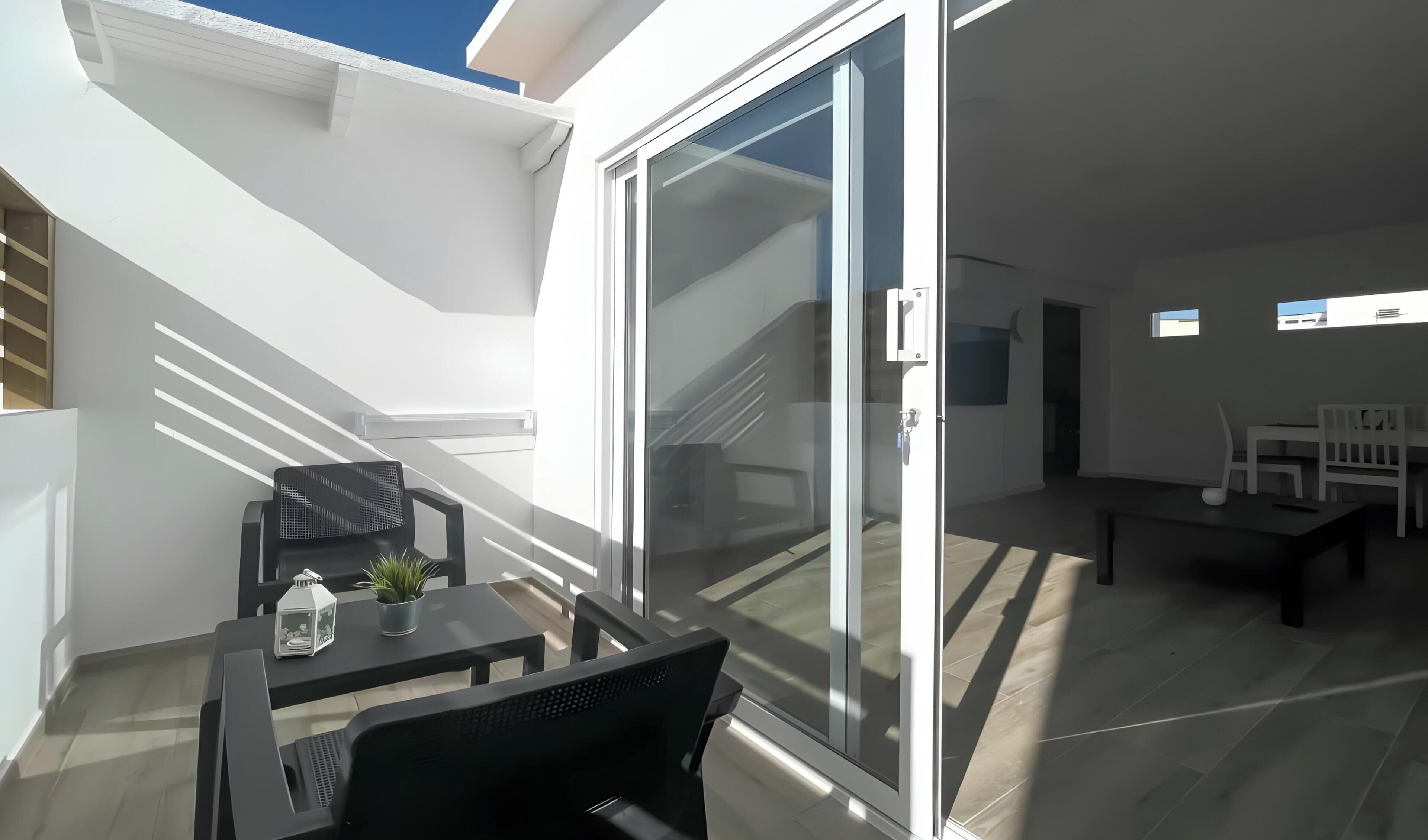 Eine moderne Terrassenanlage im Freien mit Esstisch, Stühlen und einem Blumentopf.