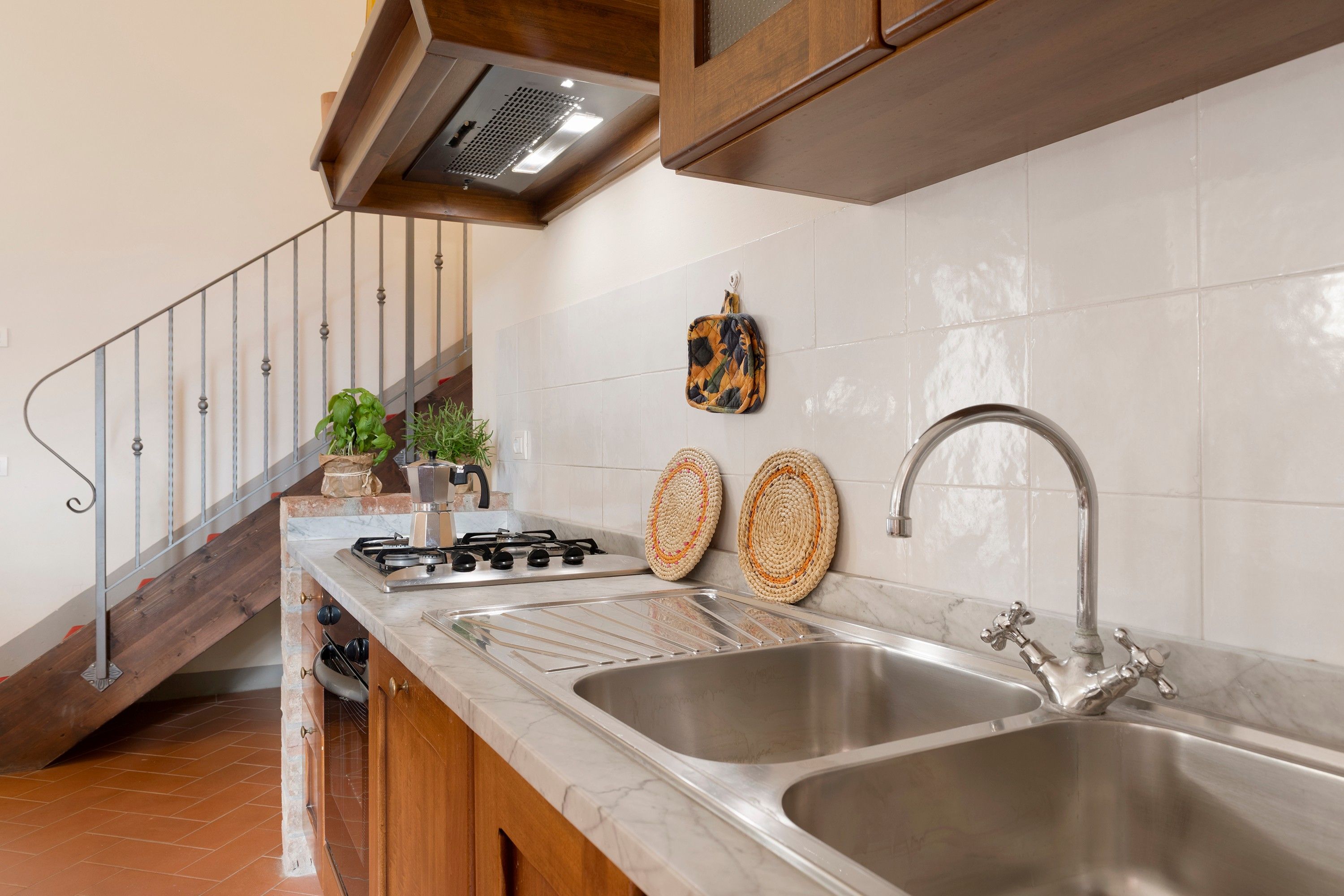 Cocina con estufa a gas, dos lavamanos, grifo de acero inoxidable y protector de salpicaduras.