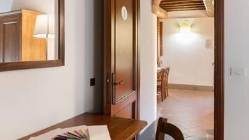 Un pasillo con una puerta de madera, un escritorio con lápices de colores y un comedor con sillas.