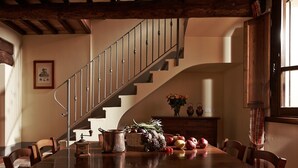 A dining area with a wooden table, chairs, a staircase, and a vase of flowers. - Querce - Spacious apartment for 8 guests with private outdoor area (Gambassi Terme)