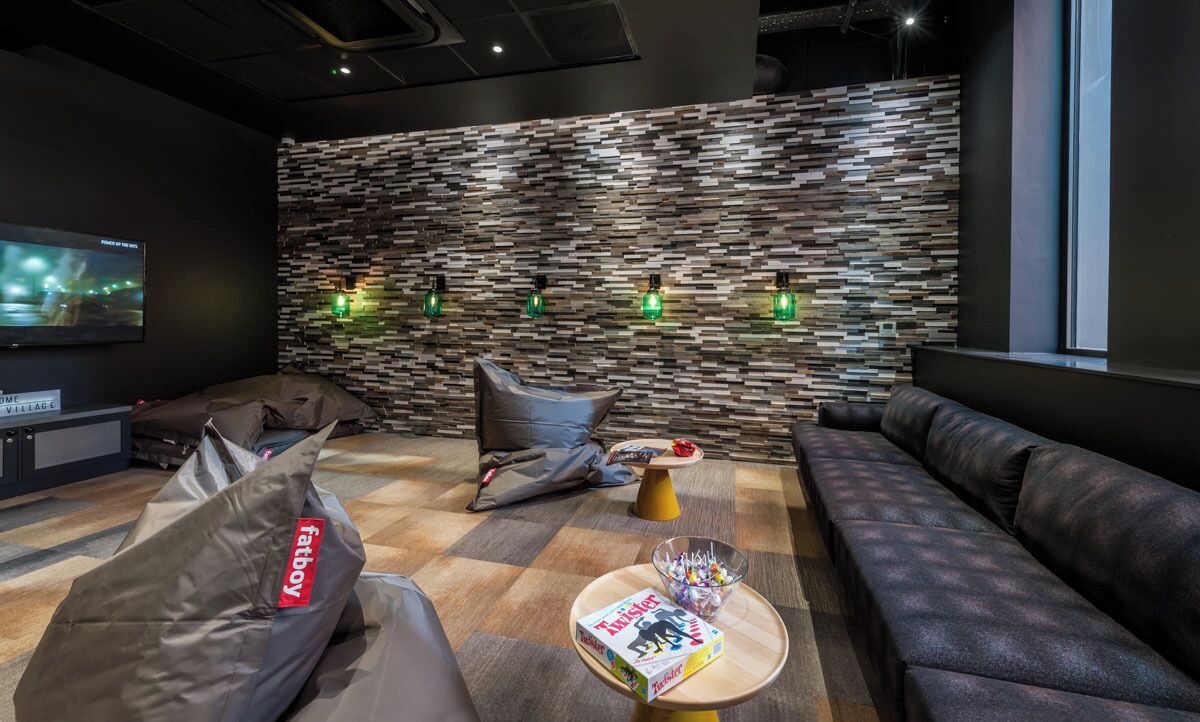 A modern lounge with a stone-patterned wall, a flat-screen TV, and comfortable seating.