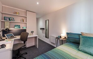 A modern bedroom with a bed, desk, chair, and shelving unit. - Student Only City Village Coventry (Coventry)