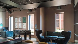 A room with a foosball table, a ping pong table, and a sofa. - Student Only City Village Coventry (Coventry)