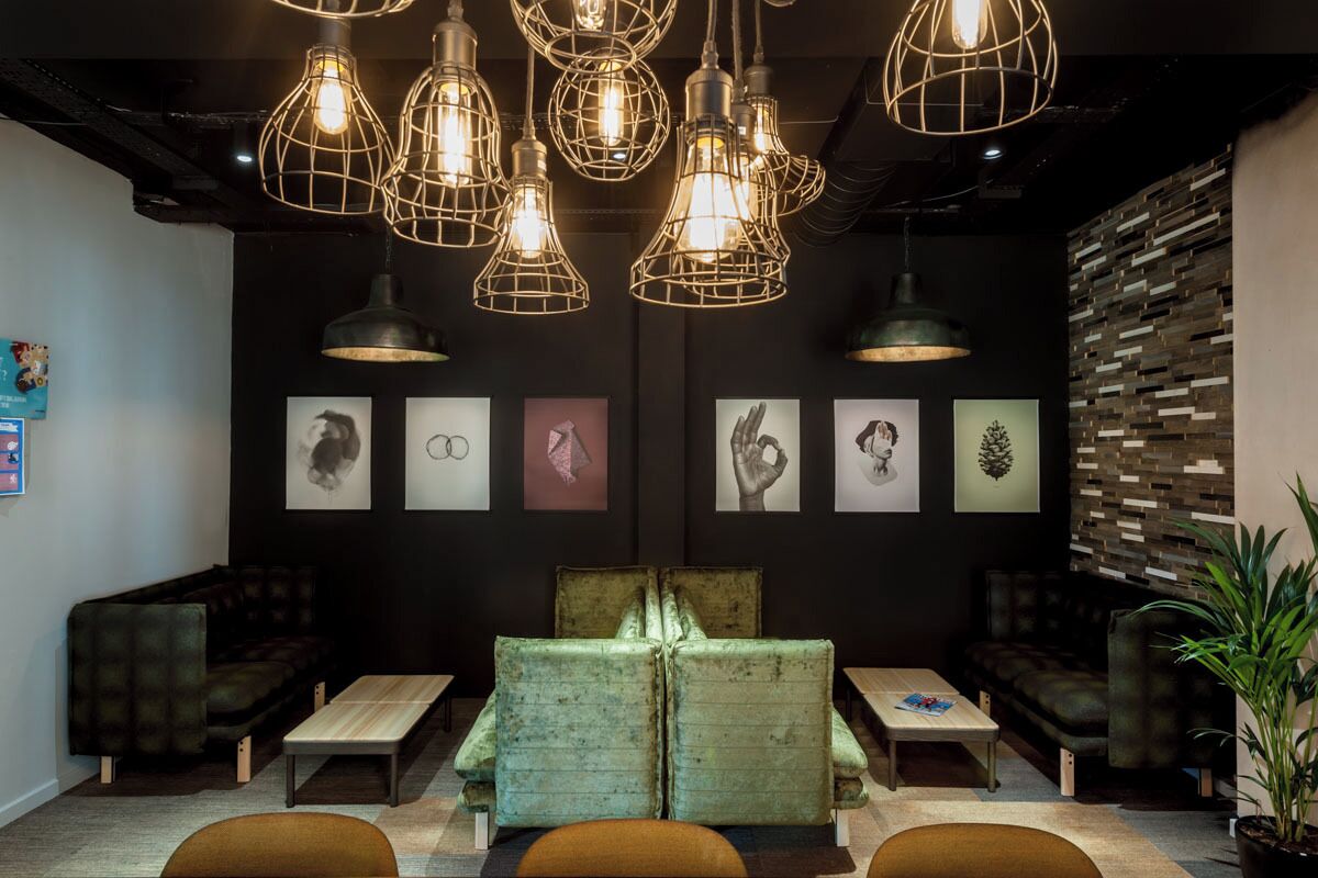 A modern lounge area with a central seating arrangement, pendant lighting, and artwork on the walls.