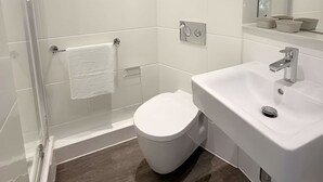 A modern bathroom with a glass-enclosed shower, a white toilet, and a sink with a mirror above it. - Student Only City Village Coventry (Coventry)