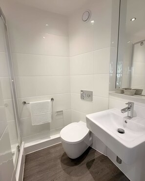 A modern bathroom with a glass-enclosed shower, a white toilet, and a sink with a mirror above it. - Student Only City Village Coventry (Coventry)