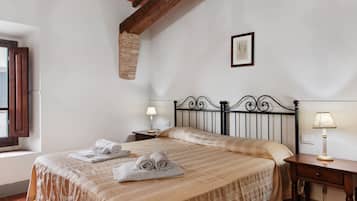 A bedroom with a bed, two bedside tables, a window, and a wall-mounted picture.