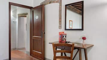 A wooden door with a number '1' sign, a mirror on the wall, and a small table with books and a vase.
