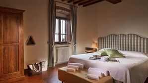 Ein Schlafzimmer mit einem großen Bett, einem Holzschrank, einem Heizkörper und einem Fenster mit Vorhängen.