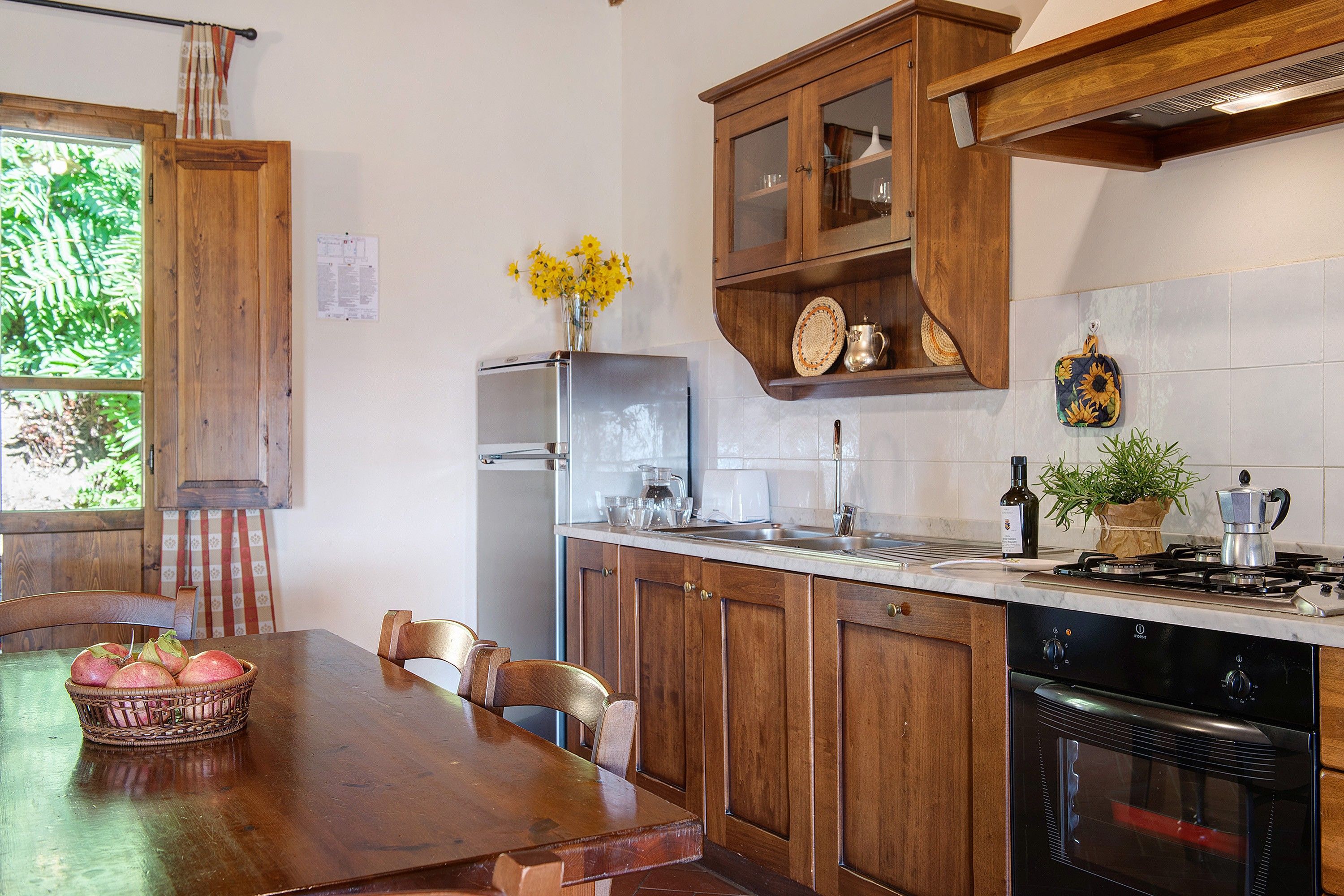 Eine Küche mit Holzausstattung, einem Esstisch mit Stühlen, einem Kühlschrank und einem Herd.