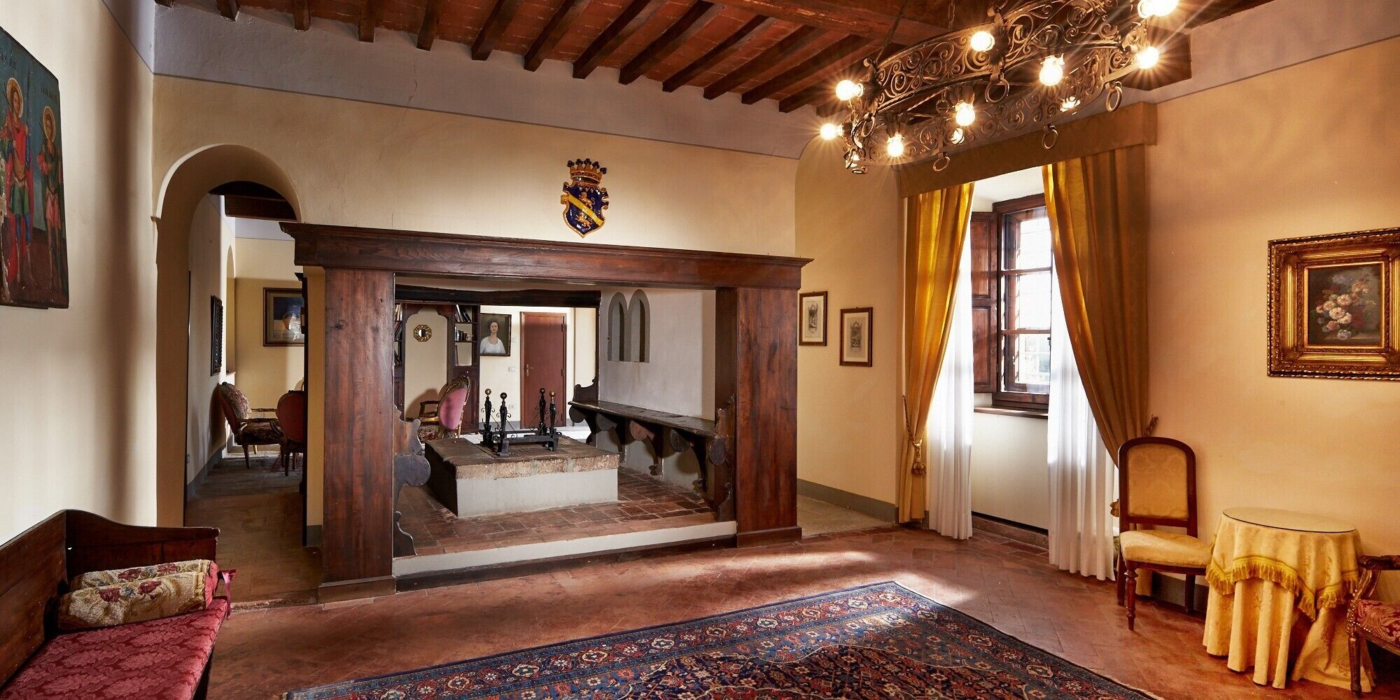 Ein traditionelles Interieur mit einer Holztreppe, einem Chandelier und einem gemusterten Teppich.
