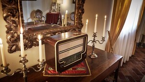 Une vieille radio posée sur une table en bois, entourée de nombreuses bougies allumées et de bougeoirs décoratifs.