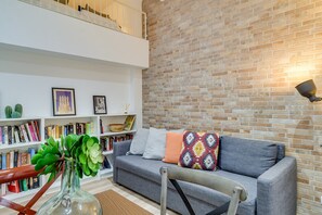 Ein modernes Wohnzimmer mit grauem Sofa, Bücherregal und einer Ziegelwand.