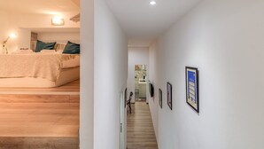 A hallway with a bed, wooden flooring, and framed pictures on the walls. - GuestReady - Charming Studio with Patio in Gràcia (Barcelona)