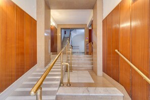 Ein Korridor mit Marmorstufen, Holzvertäfelung und einer Treppe, die zu einer anderen Etage führt.