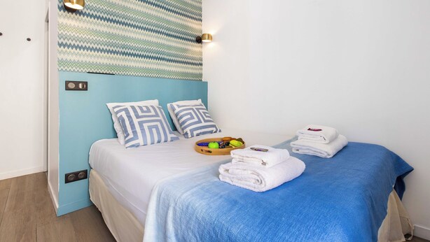 Habitación de hotel con cama, almohadas, un atril con artículos de aseo y toallas.