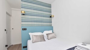 Habitación de hotel con cama, dos lámparas de noche, pared con diseño y pared de acento azul.