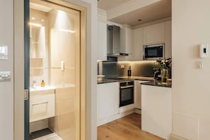 Eine moderne Küche mit weißen Schränken, einer Mikrowelle, einem Backofen und einem integrierten Geschirrspüler.