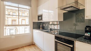 Une cuisine moderne dotée d’une grande fenêtre, d’un four à micro-ondes encastré et d’un lave-vaisselle.