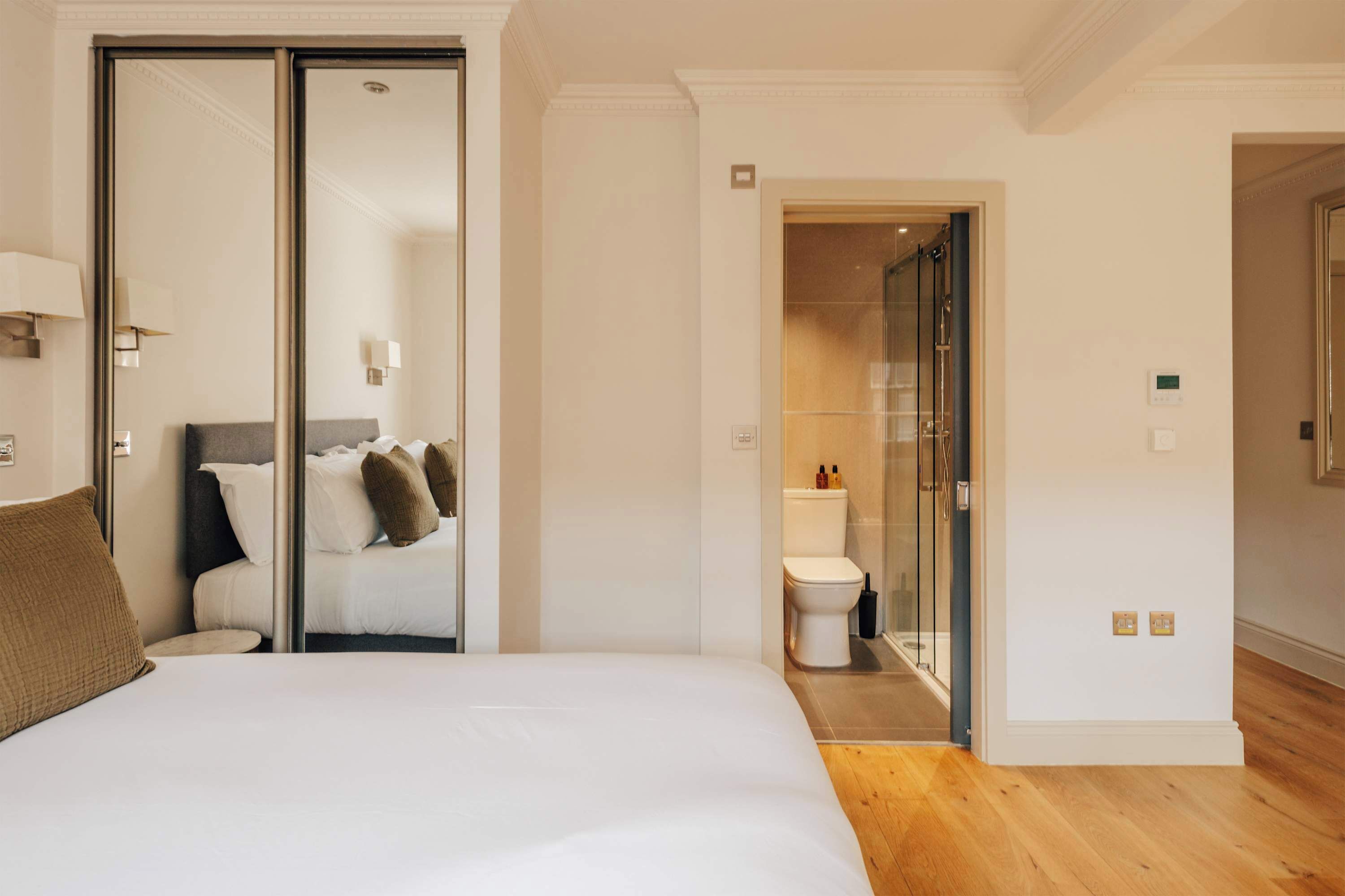 Ein Hotelzimmer mit Bett, Schrank, Badezimmer mit Toilette und Dusche sowie einem Flur.
