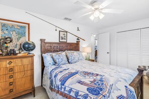 Ein Schlafzimmer mit einem Holzkopfende, einem Globus, einer Karte und einem Bett mit einem gemusterten Bettüberwurf.