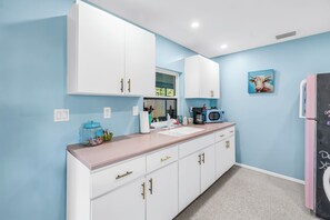 Eine moderne Küche mit weißen Schränken, einem pinken Kühlschrank und einer blauen Wand.