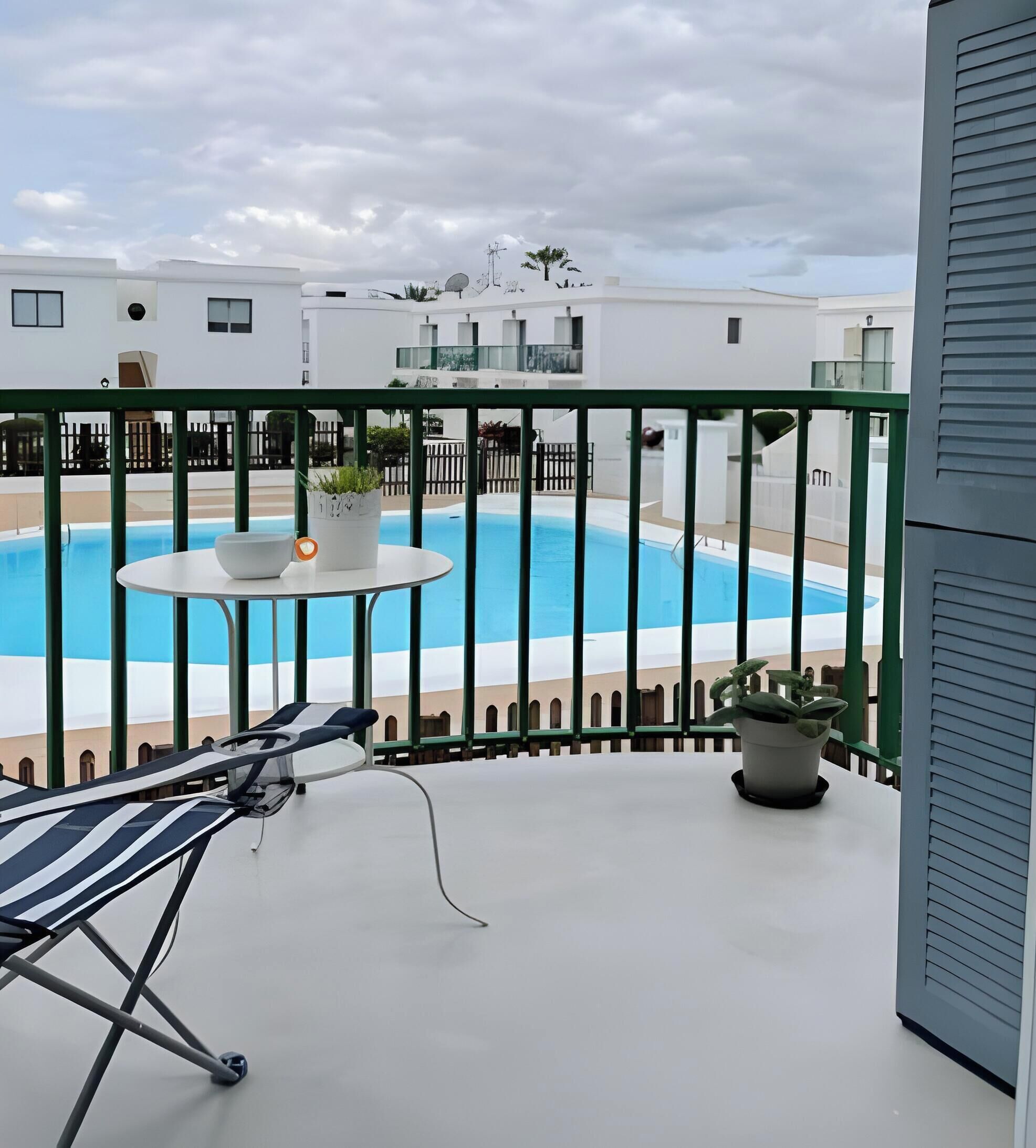 Un balcón con piscina, una silla de descanso y plantas en macetas.