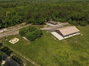 An aerial view of a property with a large covered outdoor area, a small building, and a dirt path.