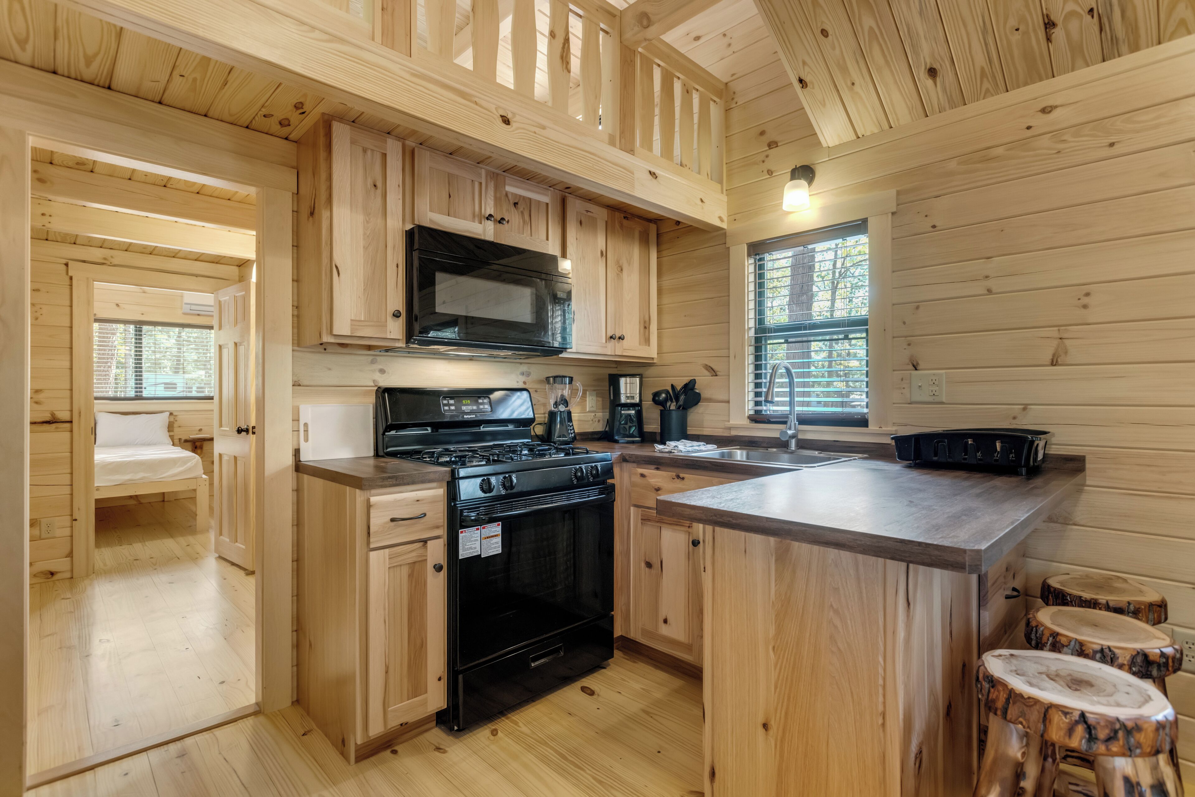 Una cocina compacta con armarios de madera, estufa, microondas y pileta.