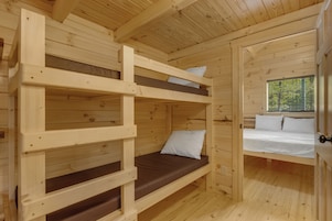 Una cabaña de madera con literas y un ventanal con persianas.