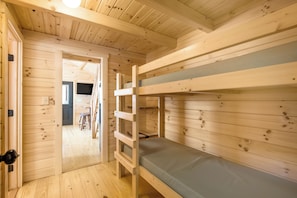 A wooden bunk bed room with a door leading to a hallway.