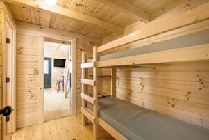 Habitación con literas de madera y una puerta que da a un pasillo.