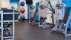 Ett gym med träningsmaskiner, en väggmonterad TV och träningsbollar.