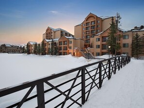 Ein mehrstöckiges Hotel, bedeckter Boden mit Schnee und ein Metallzaun.