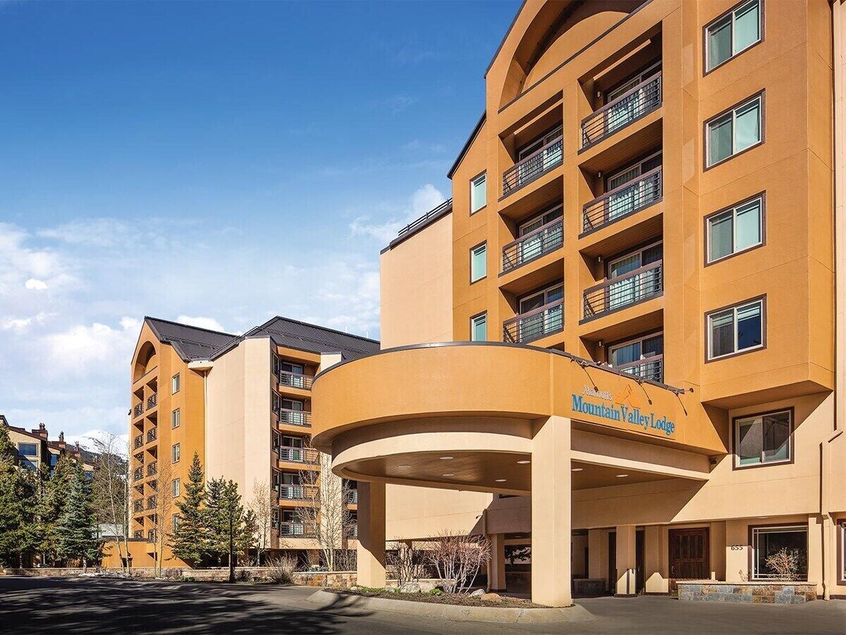 A multi-story hotel with a curved entrance, balconies, and a sign indicating it is the Mountain Valley Lodge.