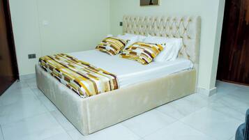 A bed with a tufted headboard, a patterned bedspread, and two pillows.
