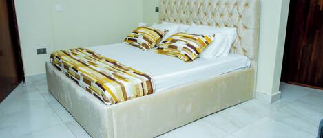 A bed with a tufted headboard, a patterned bedspread, and two pillows.